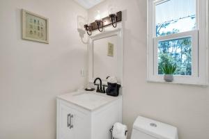 ein weißes Badezimmer mit einem Waschbecken und einem Spiegel in der Unterkunft La Niña Nokomis Beach & Venice Island Fenced In Yard in Nokomis