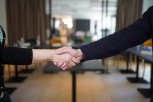 Un par de personas dándose la mano en una habitación en Campanile Troyes Sud - Buchères, en Troyes