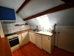una pequeña cocina con electrodomésticos blancos y una ventana en stilvolle Dachgeschoss-Wohnung in Top-Lage, en Großröhrsdorf