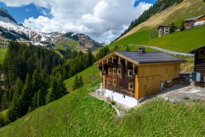 a wooden house on a hill with a mountain at Jup - a luxury boutique chalet in Warth am Arlberg