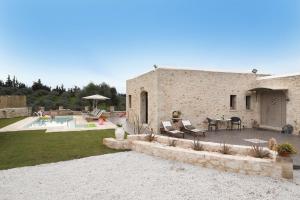 a stone house with a patio and a pool at Heliopetra Lux Villa with private Pool in Varípetron