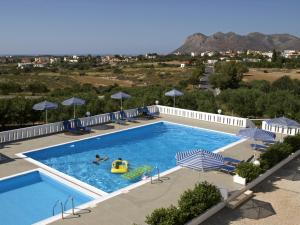 a swimming pool with umbrellas and two people playing in it at Villas Michalis in Chorafakia