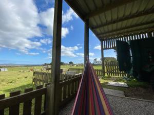a hammock on a porch with a fence and a field at Stunning views & sunrises from Sally Saracen in St Ives