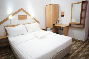 Schlafzimmer mit einem weißen Bett und einem Spiegel in der Unterkunft Golhaaviewinn in Thulusdhoo
