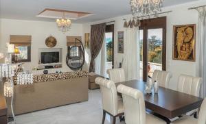 una sala da pranzo e un soggiorno con tavolo e sedie. di Heliopetra Lux Villa with private Pool a Varípetron