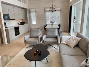 uma sala de estar com um sofá, cadeiras e uma mesa em Villa Iiris - New Holiday Home em Äkäslompolo