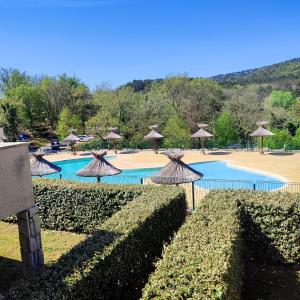 a resort with a pool with umbrellas and a swimming pool at Maison de 3 chambres avec piscine partagee jardin et wifi a Salavas in Salavas