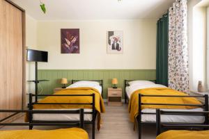2 Betten in einem Zimmer mit gelber Bettwäsche in der Unterkunft Villa Arkadia in Września