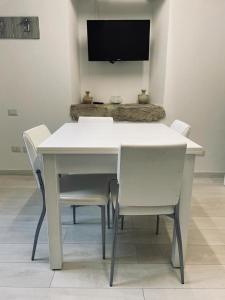 a white table and chairs with a television on a wall at Appartamenti Sole e Luna in Tropea