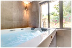 eine große Badewanne im Bad mit Fenster in der Unterkunft Le Florida Auberge contemporaine in Castéra-Verduzan