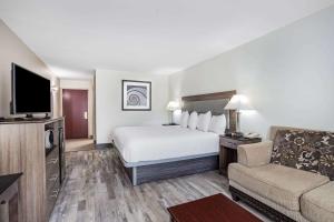 a hotel room with a bed and a couch and a television at Ramada by Wyndham Hendersonville in Hendersonville