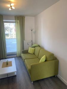a living room with a green couch and a window at Travel Apartments in Münster