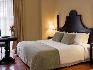 a bedroom with a large white bed with a black headboard at Novotel Cusco in Cusco