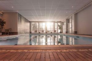 a swimming pool in a building with the sun shining at Scandic Lillehammer Hotel in Lillehammer