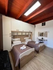 2 bedden in een kamer met houten plafonds bij Affittacamere Vicino al Porto in Porto Torres