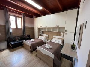 een kamer met 3 bedden en een bank bij Affittacamere Vicino al Porto in Porto Torres