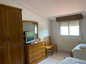 a bedroom with a dresser with a television and a bed at Hostal Sequeiros in San Ciprián de Viñas