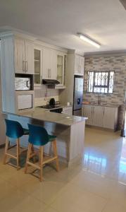 uma cozinha com um balcão e duas cadeiras azuis em Labas Travellers Guesthouse em Jozini