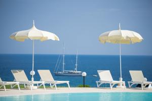 レ・カステッラにあるLe Castella Resort & Beachのスイミングプールの隣の椅子とパラソルのグループ