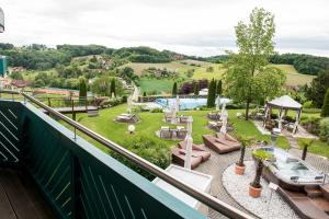 a balcony with a view of a garden and a pool at Maiers Kuschelhotel Loipersdorf Deluxe - ADULTS ONLY in Loipersdorf bei Fürstenfeld