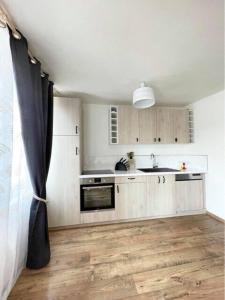 cocina con armarios blancos y suelo de madera en Le Cottage Family, en Rouen