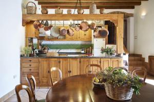 cocina con mesa de madera, sillas, ollas y sartenes en Lagar La Pizarra Casa Rural, en Trujillo