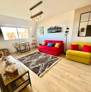 salon z dwiema czerwonymi i żółtymi kanapami oraz stołem w obiekcie Studio Les Marines - Belle Vue Mer w mieście Cabourg