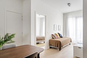a white bedroom with a bed and a mirror at Smartflats - Bell Tower Ghent in Ghent