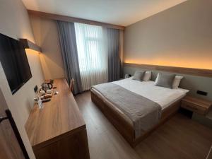 イスタンブールにあるFuar Hotelのベッドと木製テーブルが備わるホテルルームです。