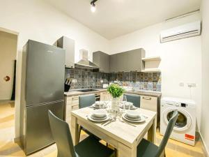 y cocina con mesa, sillas y nevera. en Well designed 3rd floor one bedroom Apt in Gzira 7, en Il-Gżira
