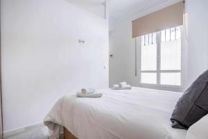 biała sypialnia z łóżkiem i ręcznikami w obiekcie COMFY AWAY - Apartamento Deluxe Centro Histórico w Sewilli
