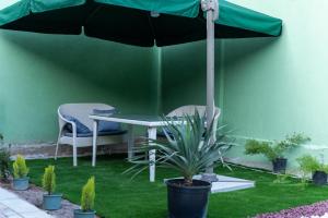 a table and chairs under a green umbrella at La Casa EmilioAngi in Yerevan