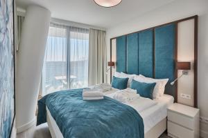 1 dormitorio con 1 cama grande y cabecero azul en Wave - Gold Suite Sea View, en Międzyzdroje