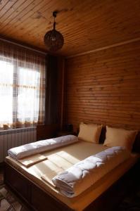 a large bed in a room with a wooden wall at Ваканционно селище Ива in Sarnitsa