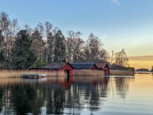Björkö的住宿－Vägs Ände Stugor，水体中间的红色谷仓