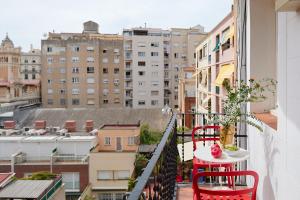 einen Balkon mit einem roten Tisch, Stühlen und Gebäuden in der Unterkunft Casa Cosi - El Farro 1 in Barcelona