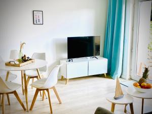 - un salon avec une télévision, une table et des chaises dans l'établissement FeWo STRANDGUT- Familien - Hunde - strandnah - eigene Terrasse - Sauna & Wellness, à Sierksdorf