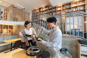 a man and a woman preparing food in a kitchen at Relief Kokura ANNEX Book & Stay in Kitakyushu