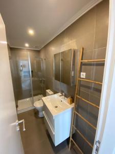 Carcavelos beach walking distance room in shared apartment في أويراس: حمام مع حوض أبيض ومرحاض