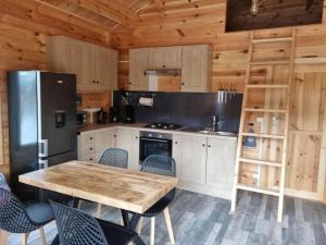 een keuken met een houten tafel en een koelkast bij Cabane pilotis sur étang, au lac de Chaumeçon in Saint-Martin-du-Puy