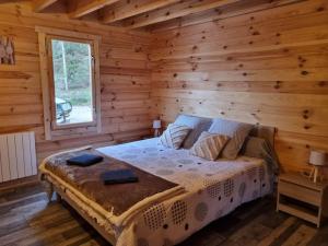 1 dormitorio con 1 cama en una cabaña de madera en Cabane pilotis sur étang, au lac de Chaumeçon, en Saint-Martin-du-Puy