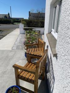 two wooden benches sitting on the side of a building at Dairy Cottage in Swordale