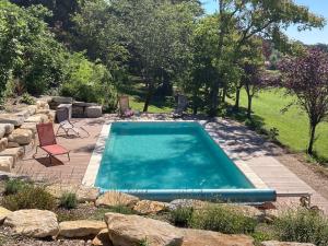 a swimming pool in a yard with chairs and trees at La nature des Sens - Gîte les Sources in Azerat