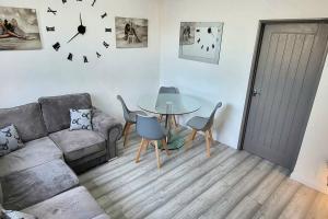 uma sala de estar com um sofá, uma mesa e um relógio em Cosy 3 double bed flat sleeps 6 em Bedworth