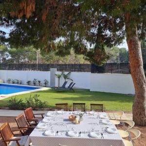 a table with plates on it next to a pool at Acogedora Villa en Alicante capital con barbacoa in Alicante