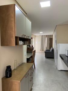 a kitchen with white cabinets and a living room at ARCO IRIS KITNETS in Fortaleza