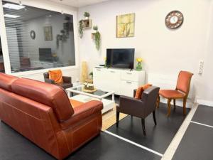 salon z kanapą, krzesłami i telewizorem w obiekcie Le clos notre Dame proche du bord de mer w Hawrze