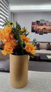 een vaas gevuld met oranje bloemen in een woonkamer bij Sunshine Apartments in Kragujevac