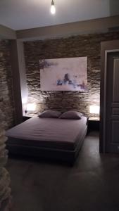 - une chambre avec un lit et un mur en pierre dans l'établissement Aegean Deep Blue Andros Ano Aprovato, à Apróvaton