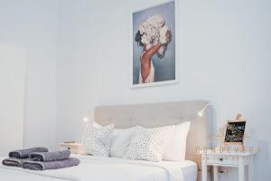 Un dormitorio blanco con una cama blanca con una foto encima. en Vv CONDEVEGA, en Telde